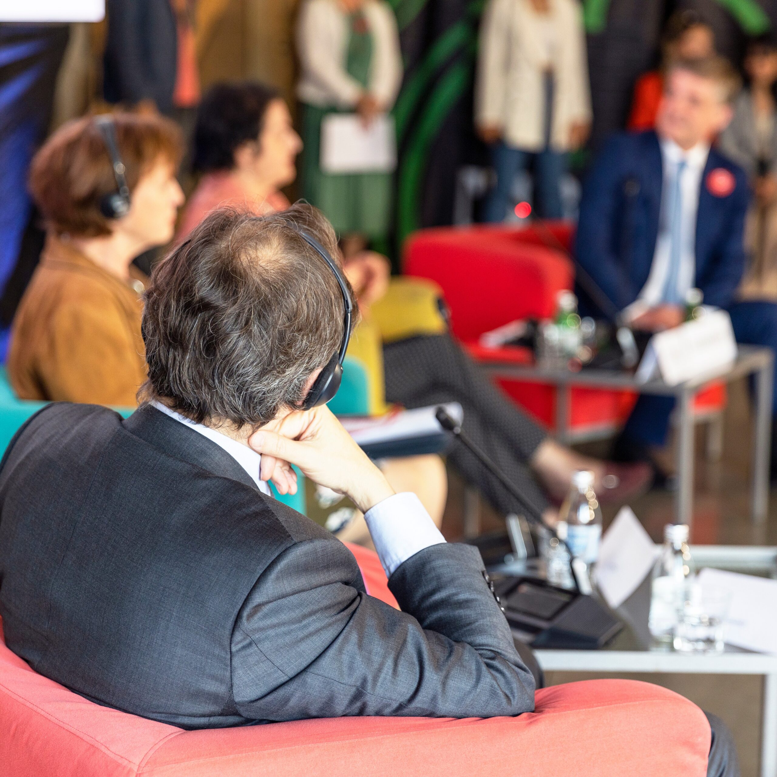 A roundtable conversation with panelists wearing headphones for real-time translation
