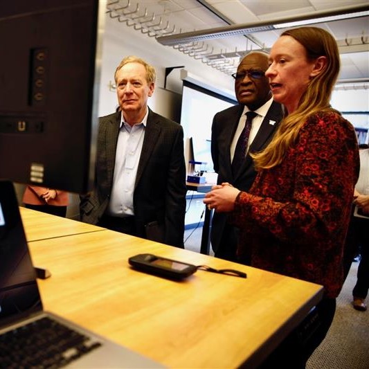Amelia Keyser-Gibson (right), a graduate student in the School of Environmental and Forest Sciences, demonstrates her research to UW President Robert J. Jones (center) and Microsoft Vice Chair and President Brad Smith (left).