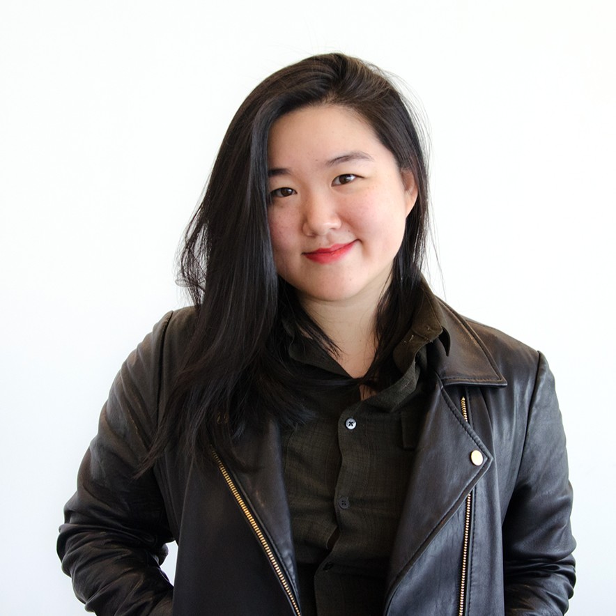 An image of Emily Tseng, who is wearing a black leather jacket over a dark button-up shirt